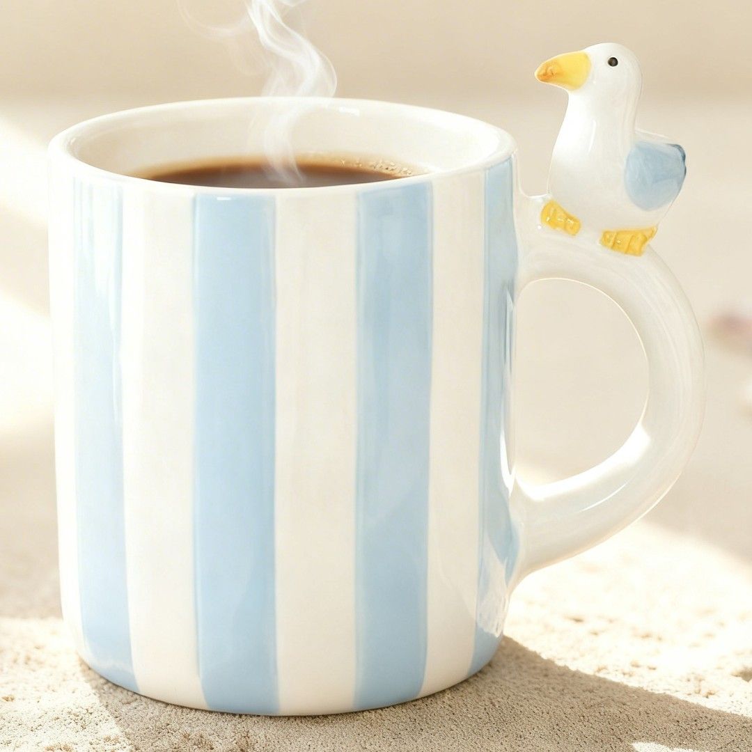 Blue and white striped seagull mug on sand, coastal styling