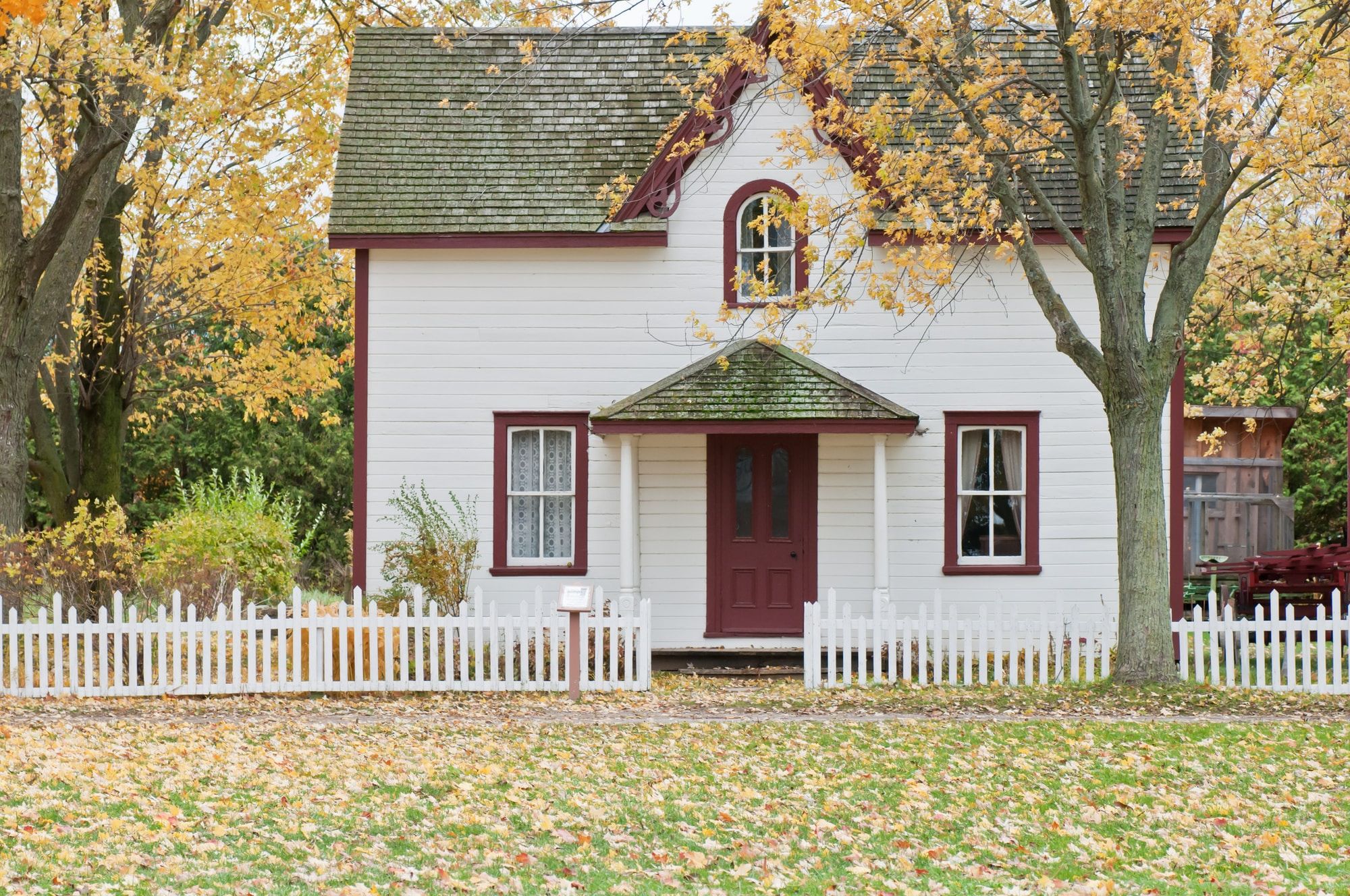 A country home painted white with red doors and windows