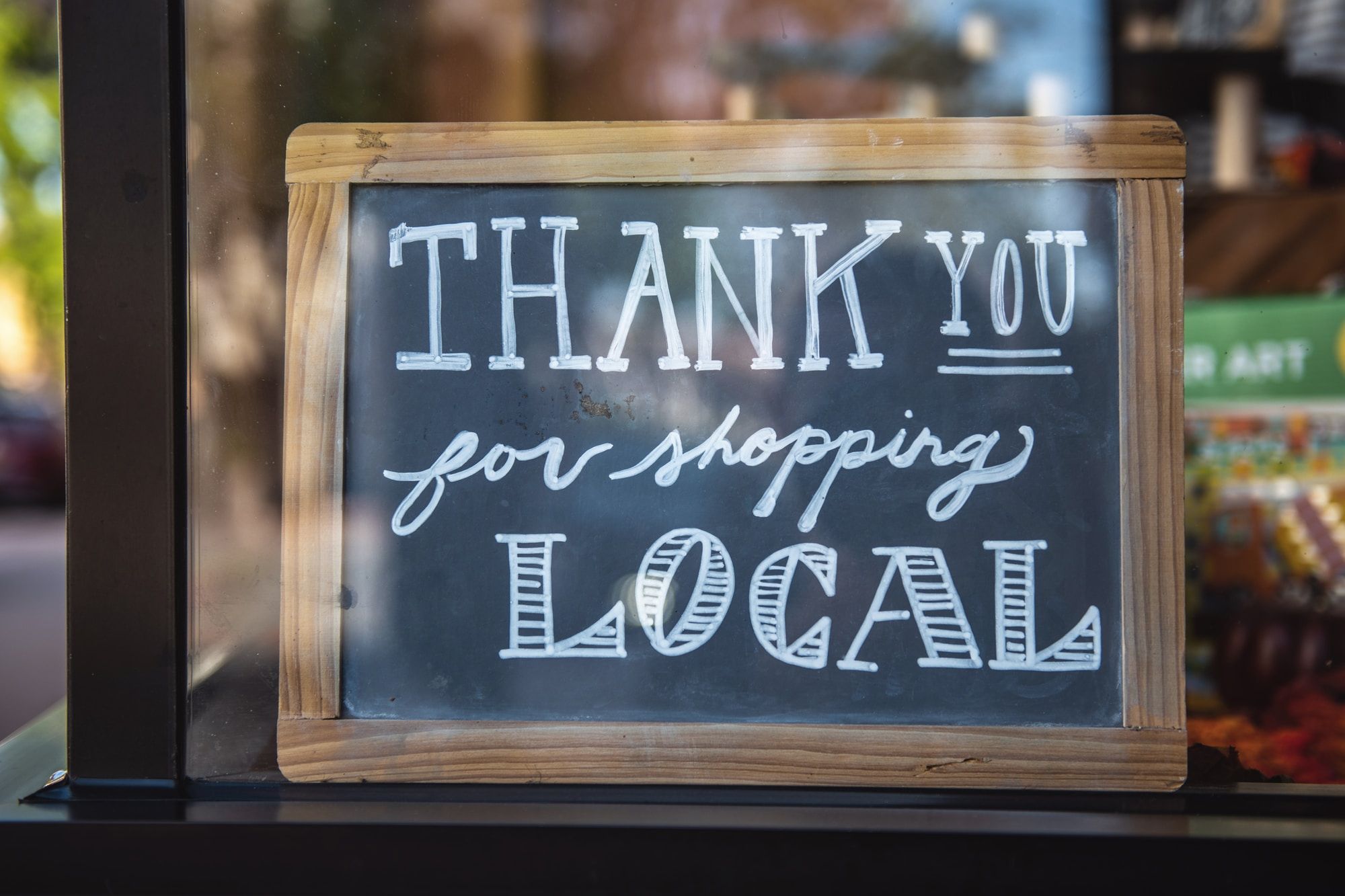 A sign in a shop window saying "Thank you for shopping local"