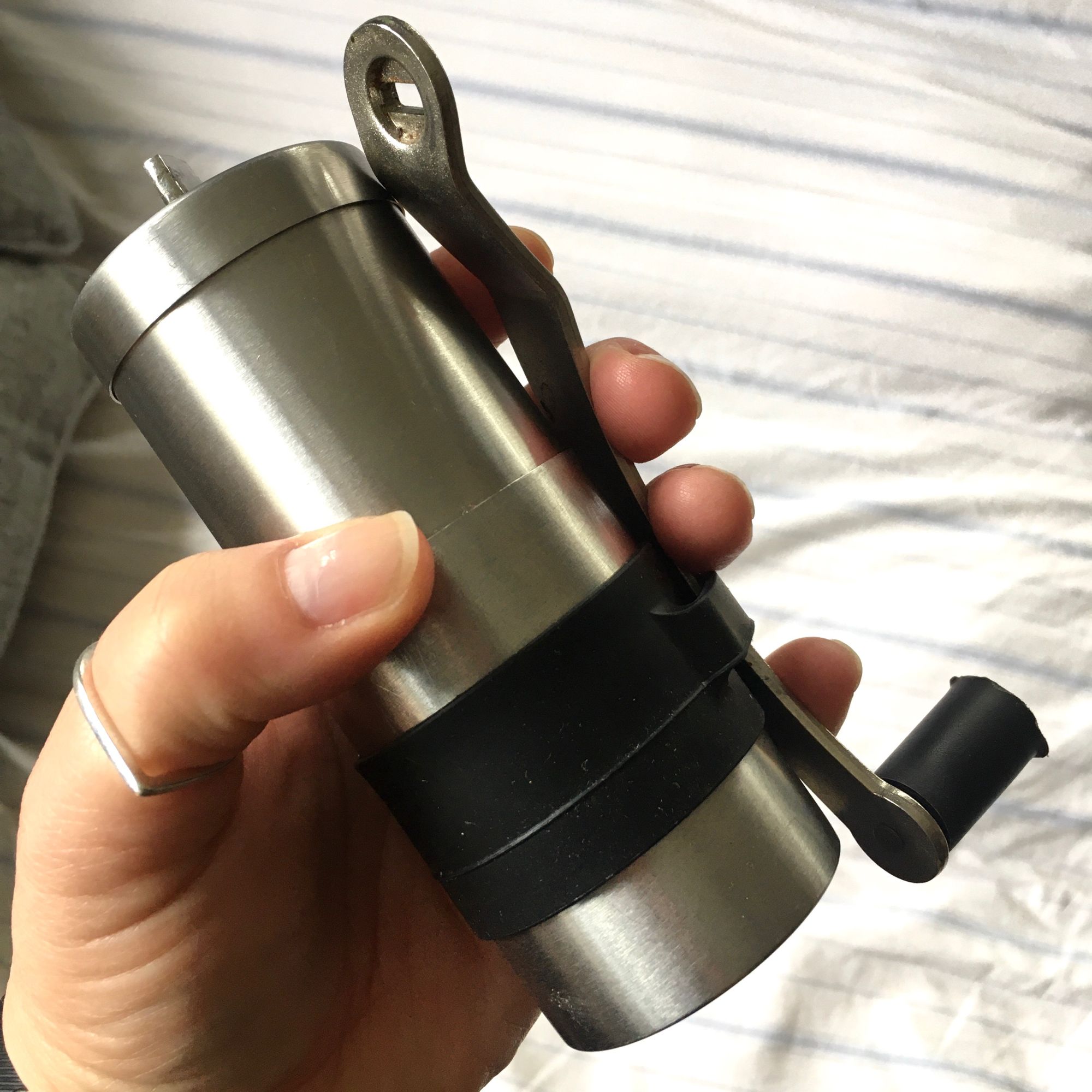 A silver coffee grinder being held.