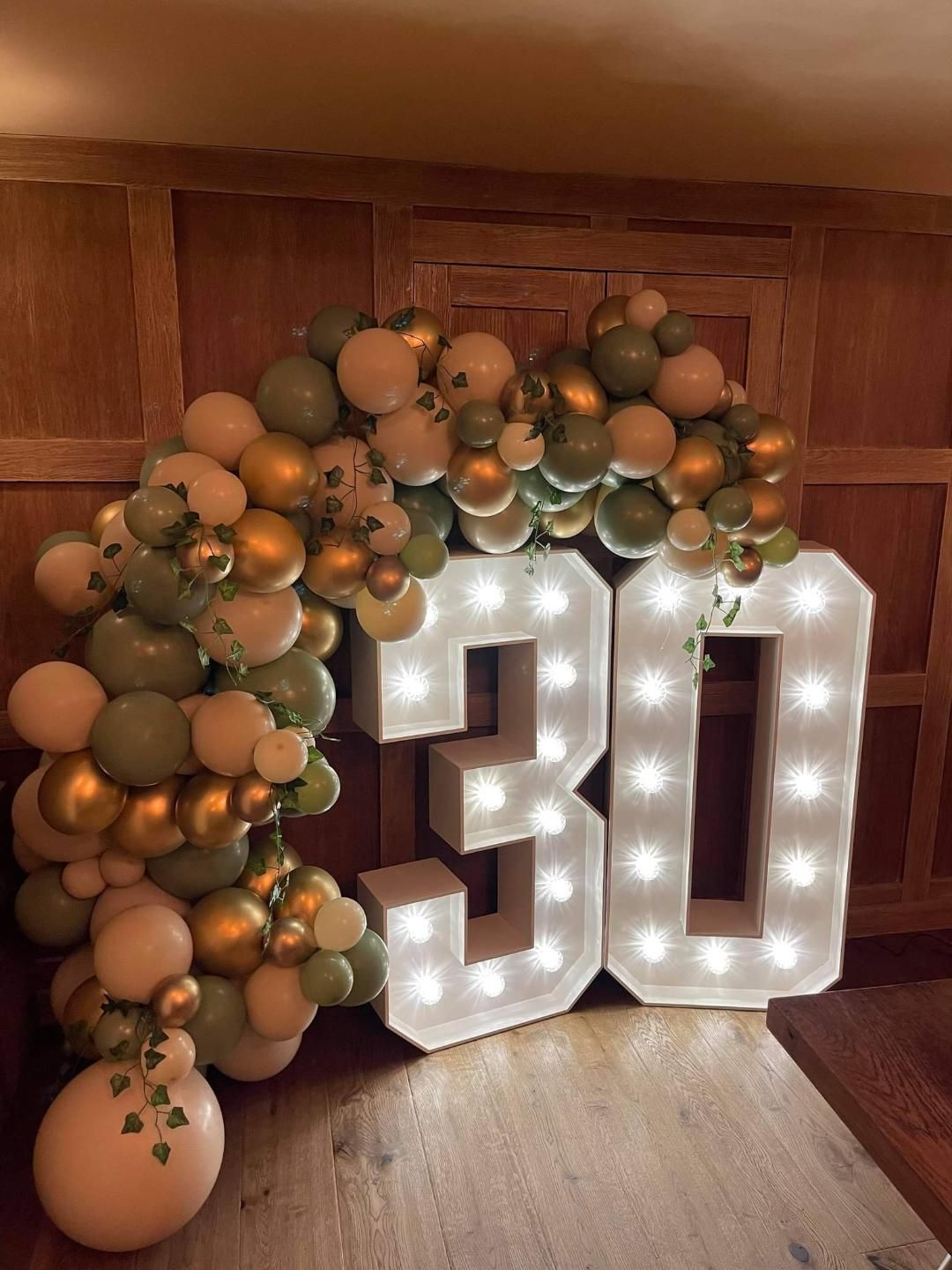 Light Up 30 Numbers with balloon garland in cream, green and gold with ivy