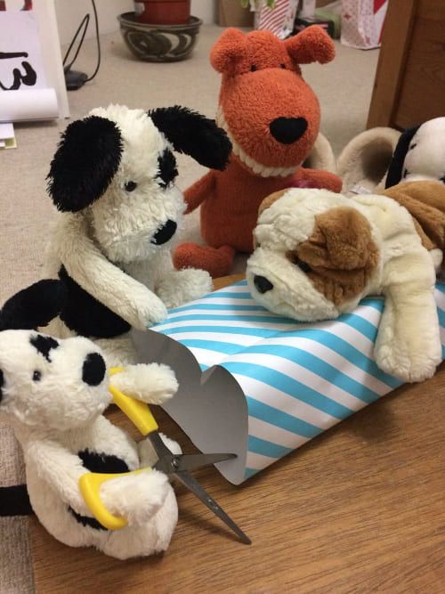 Stuffed dog teddies wrapping up a present. Albert, Mini Chops & Mini Bob - Packaging Team.