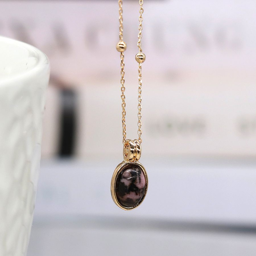 Golden necklace with small oval pink and black stone