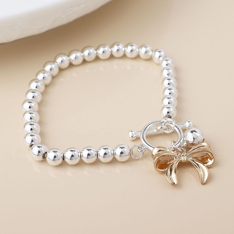 Silver plated bell and golden bow charm bracelet