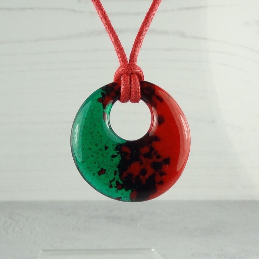 Handcrafted fused glass green and red pendant on a waxed cotton cord