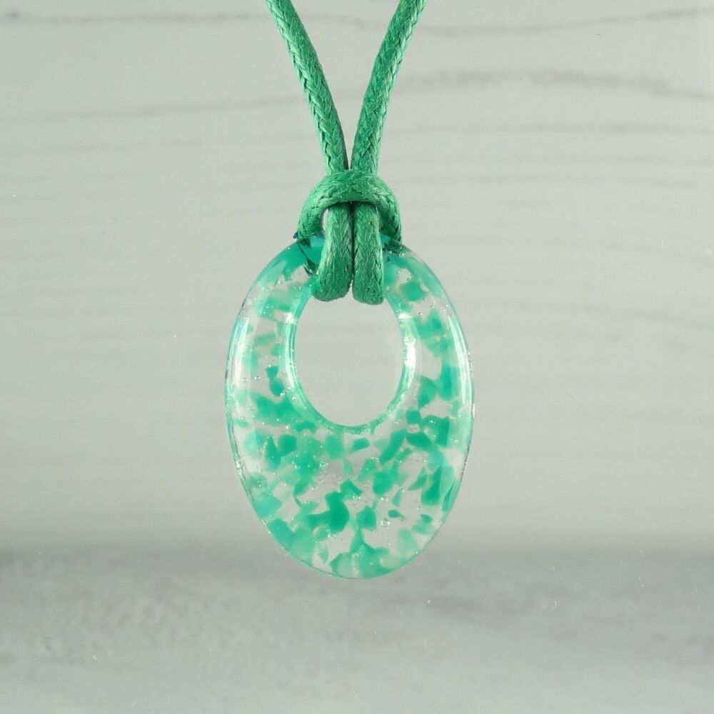 Handcrafted teal green fused glass off-set oval pendant on a waxed cord