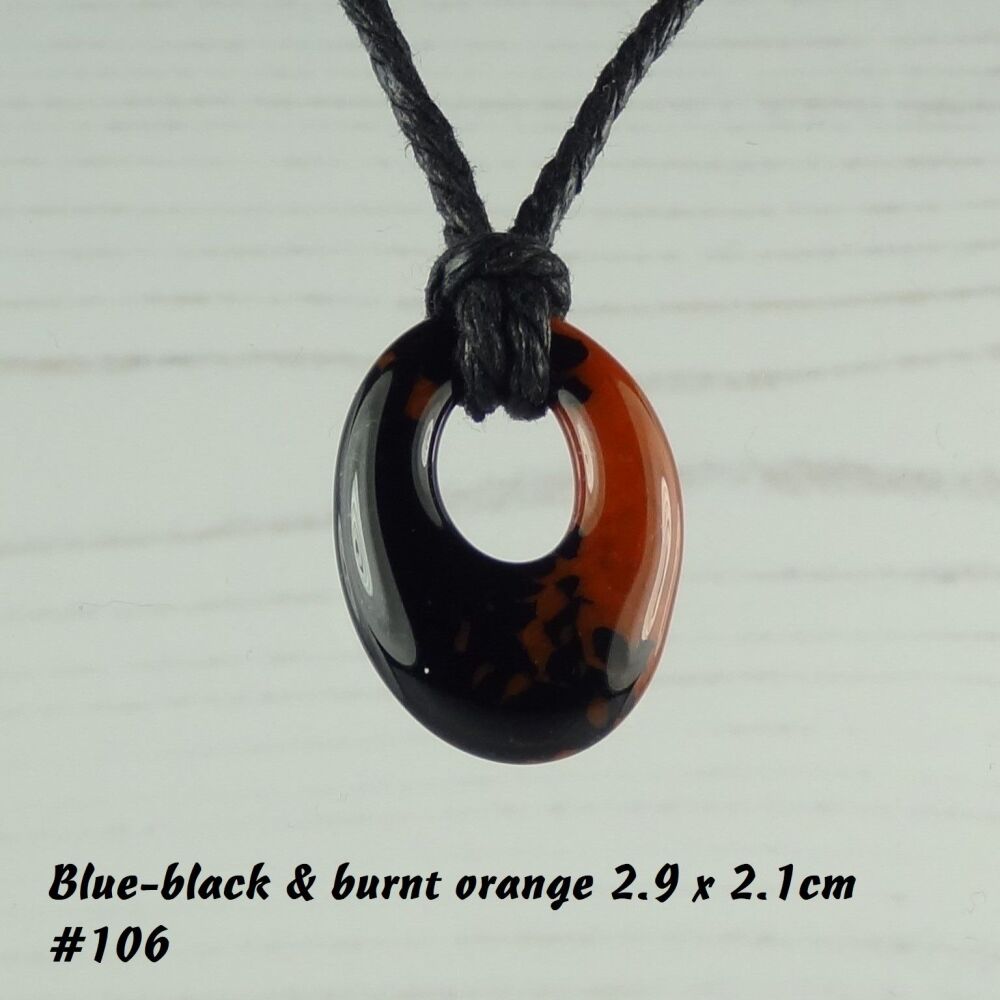 Handcrafted burnt orange & black-blue fused glass off-set oval pendant on a waxed cotton cord with lobster clasp (#106)