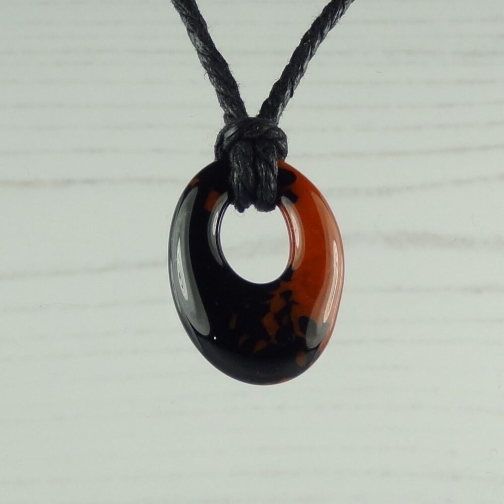 Handcrafted burnt orange & blue-black fused glass oval pendant on a cord