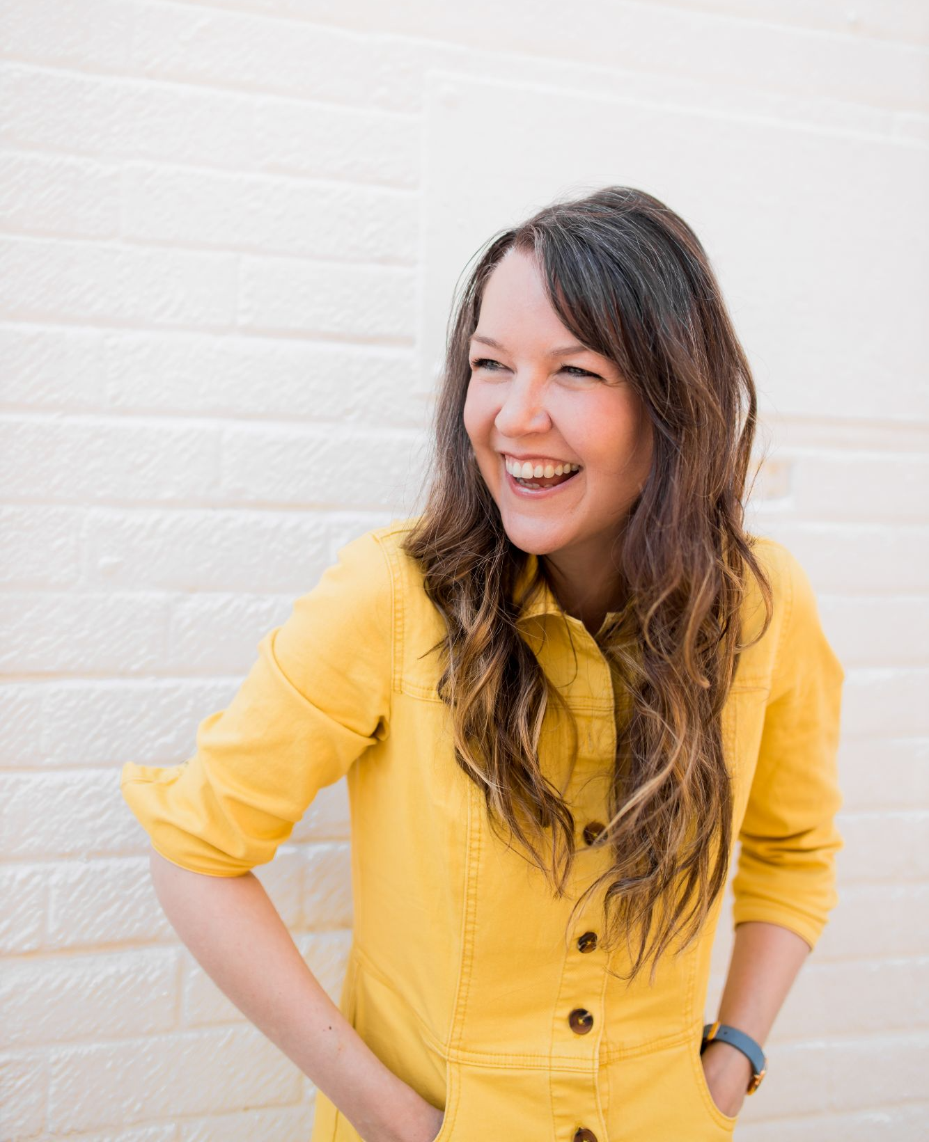 Brighton headshot photographer Lauren Psyk laughing in the street wearing a yellow dress