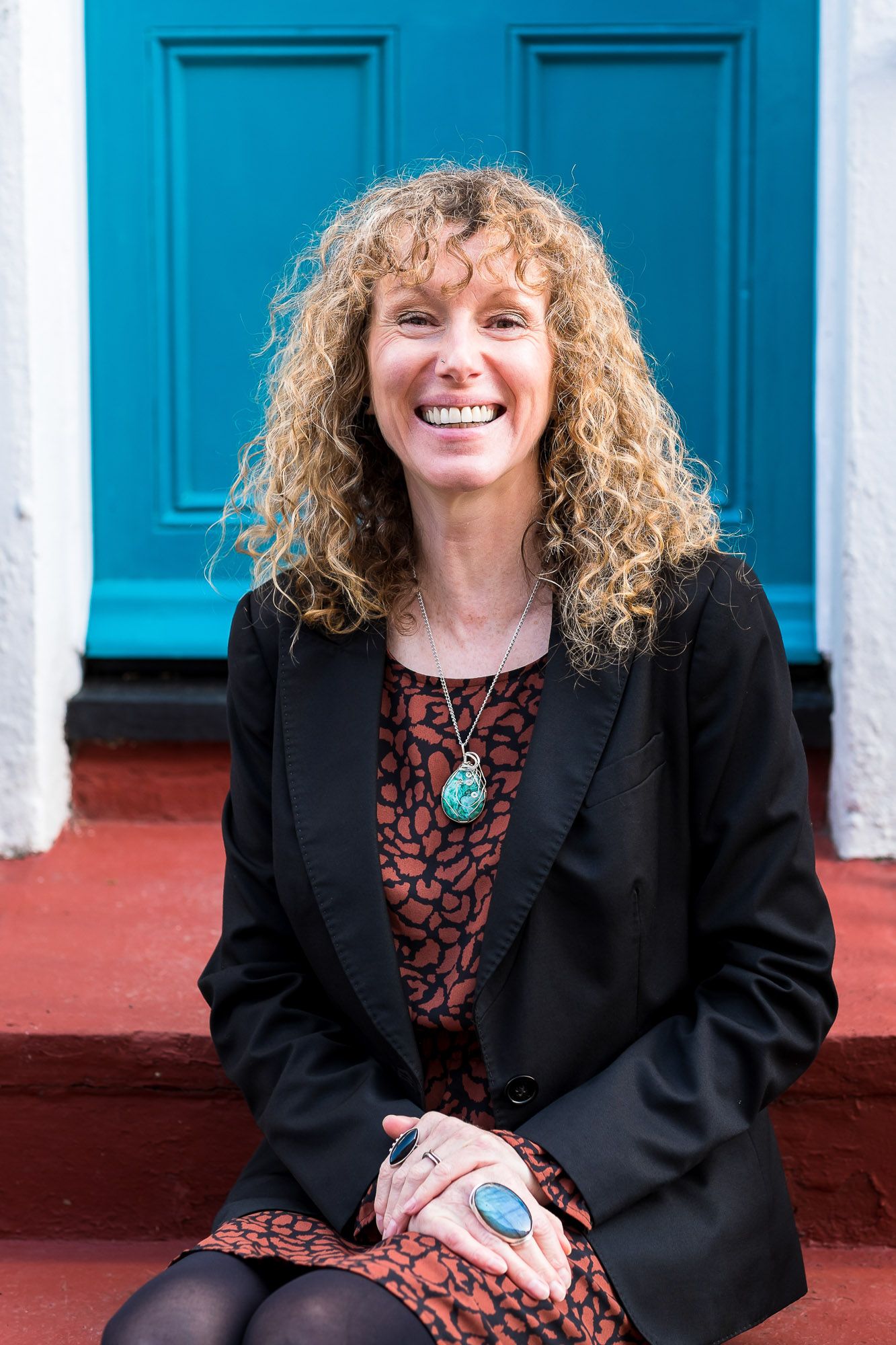 Leadership coach Jo Murfin sitting on a step in the street in Brighton in front of a blue door