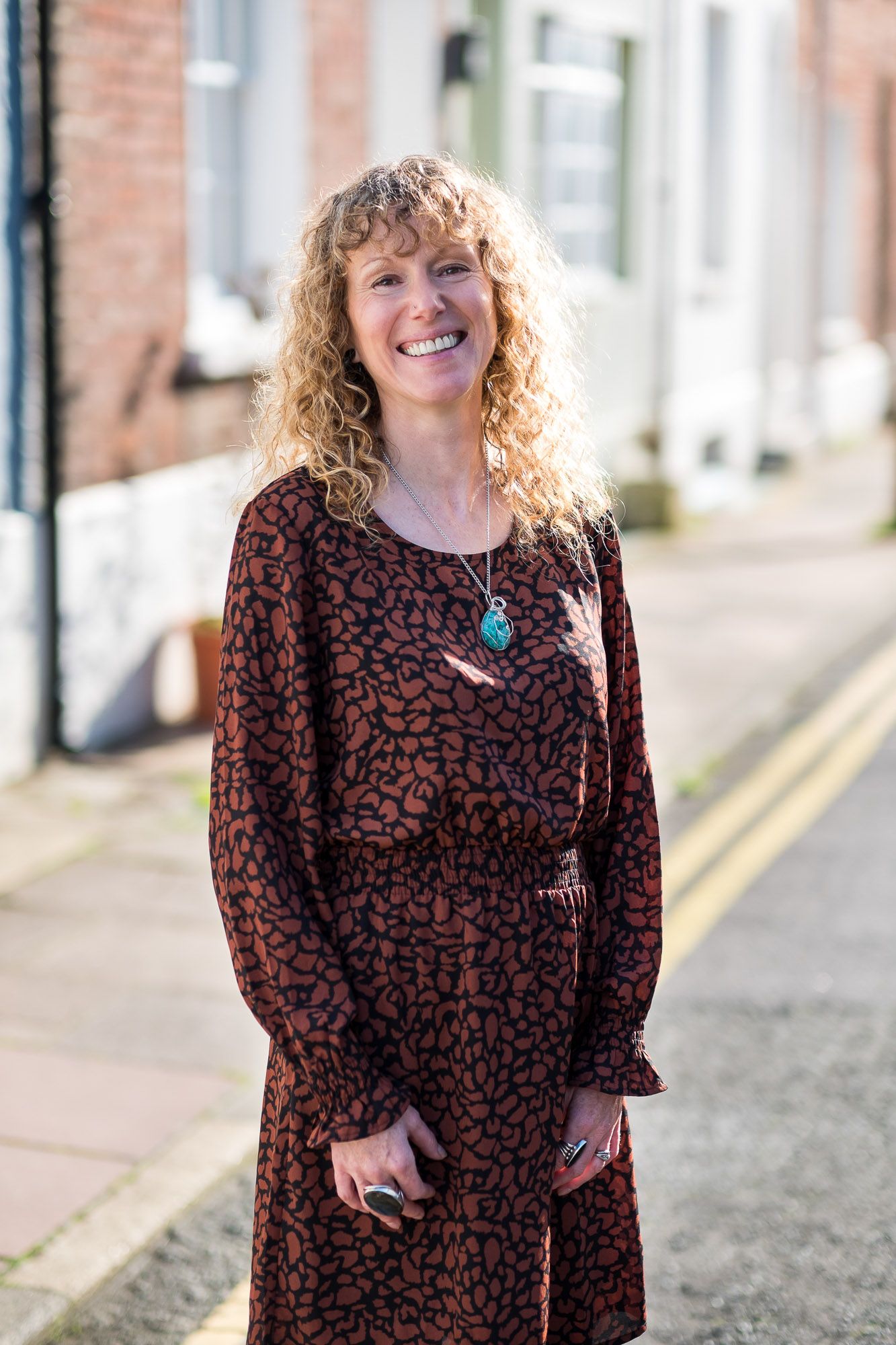 Leadership coach Jo Murfin standing in a street in Brighton wearing a brown dress smiling