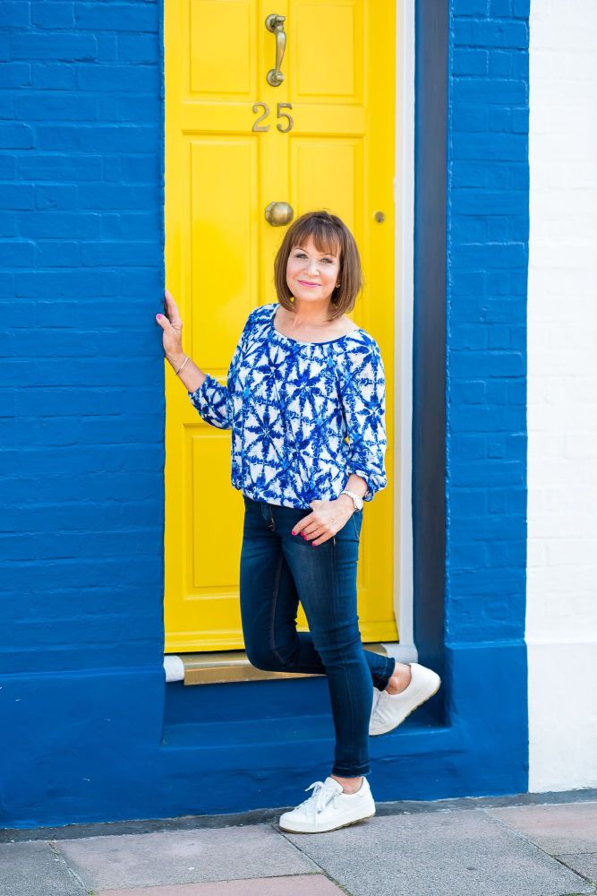 Woman standing on the step of a blue and yellow coloured house in Brighton