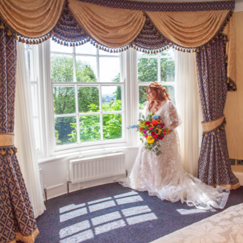 Picture of a bride groom and flowergirls on their wedding day, with a multicoloured rainbow bridal bouquet, full of sunflowers, roses, peony and foliage