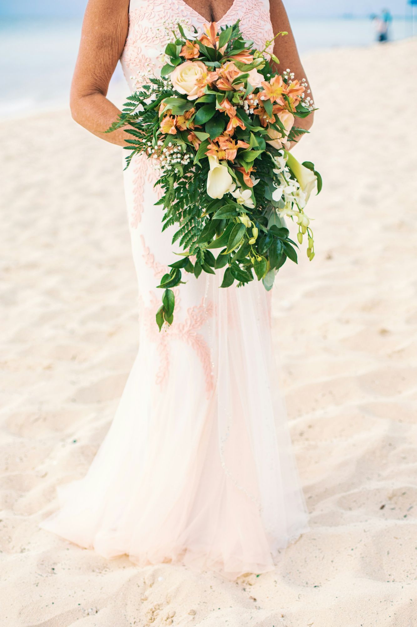 a-woman-holding-a-bouquet-of-flowers-on-a-beach-28lq9AoGbCU.jpg
