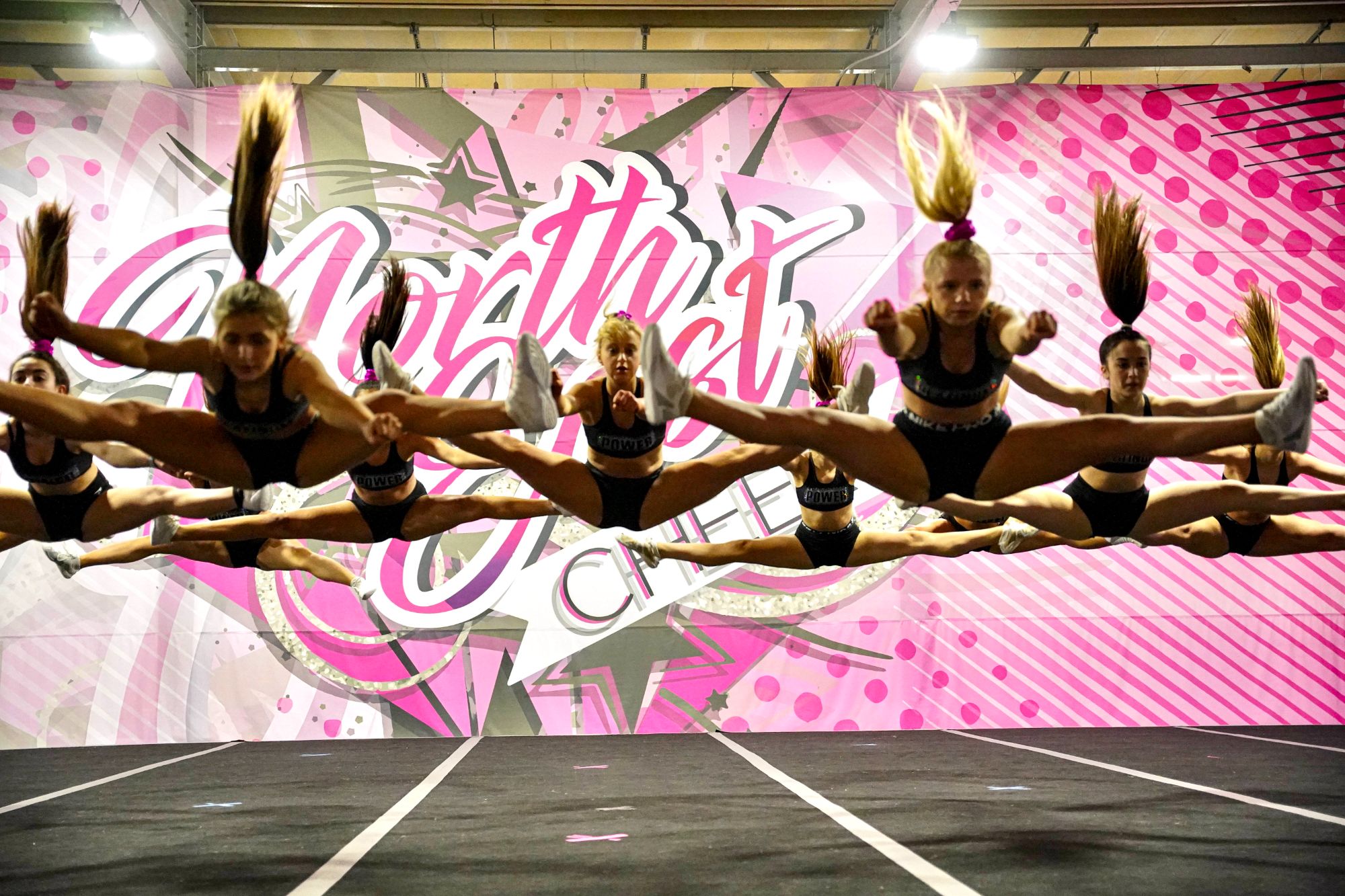 A group of girls all doing split jumps at the same time.