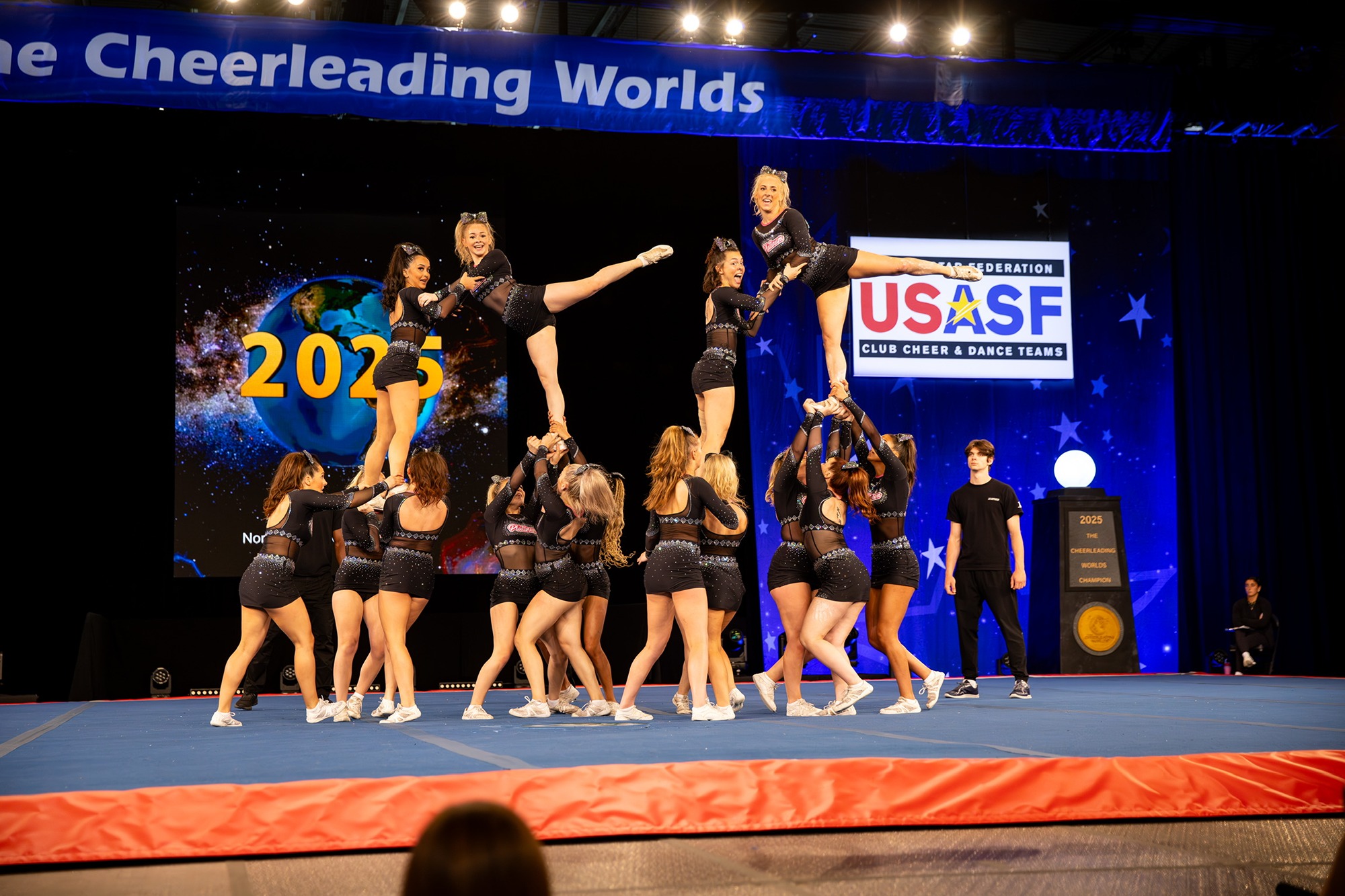 Multiple girls doing cheer, where five girls are held up  in a position by the others.