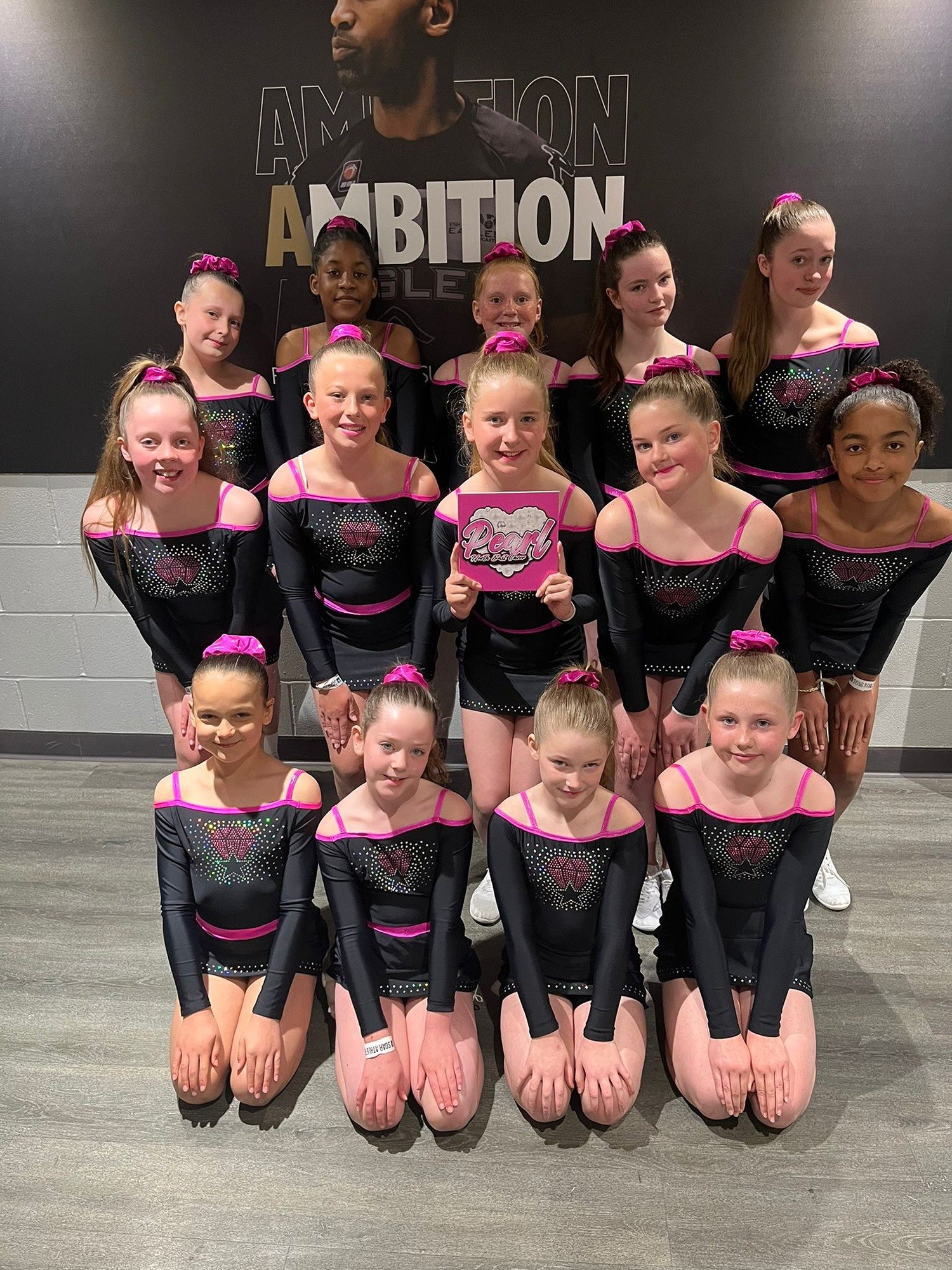 A group photo of young girls in cheer outfits all smiling.