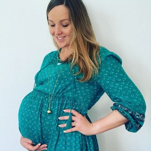 the hypnobirthing teacher when she was pregnant - she is smiling and looking at her bump