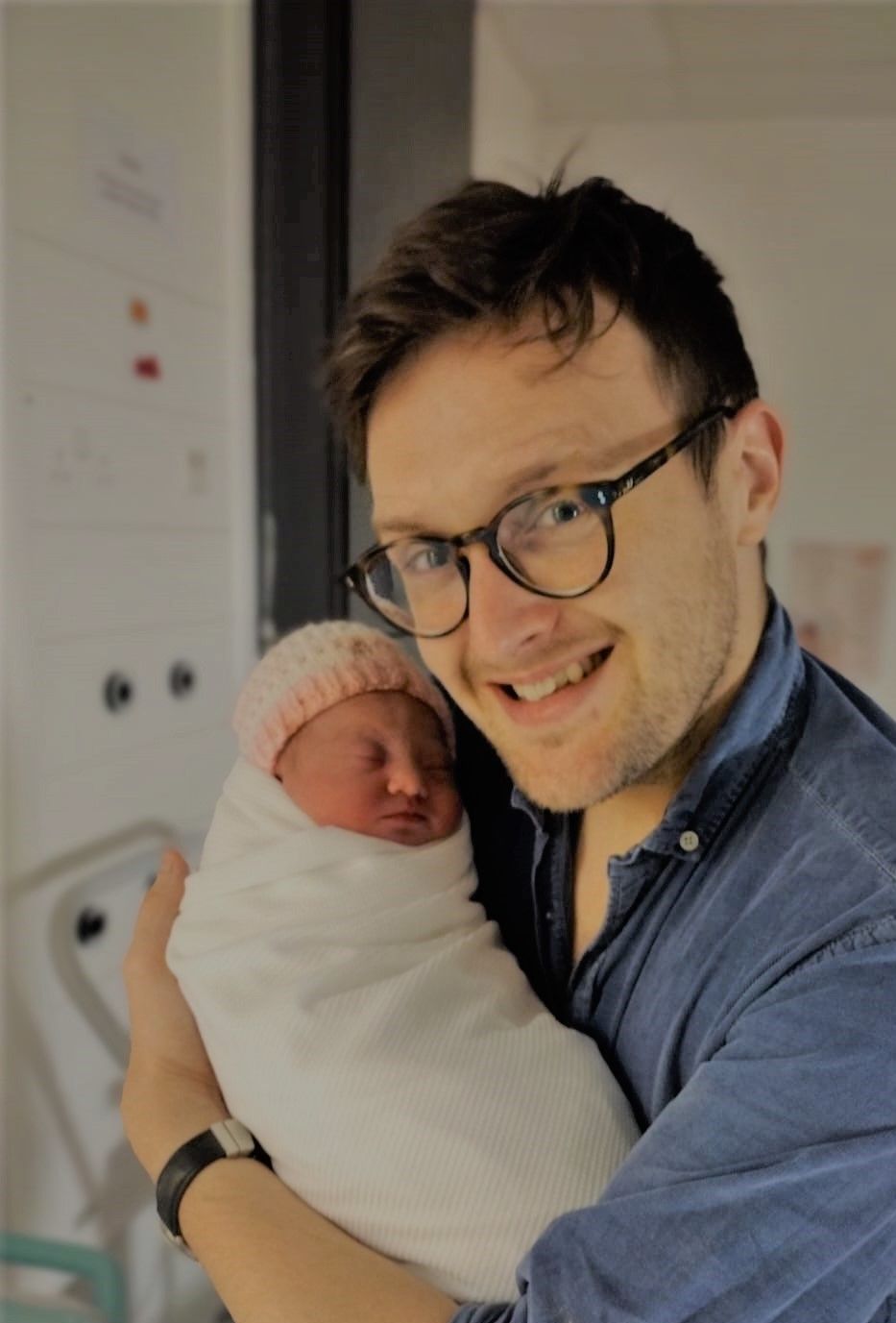 hypnobirthing new dad and birth partner smili8ng and holding new baby