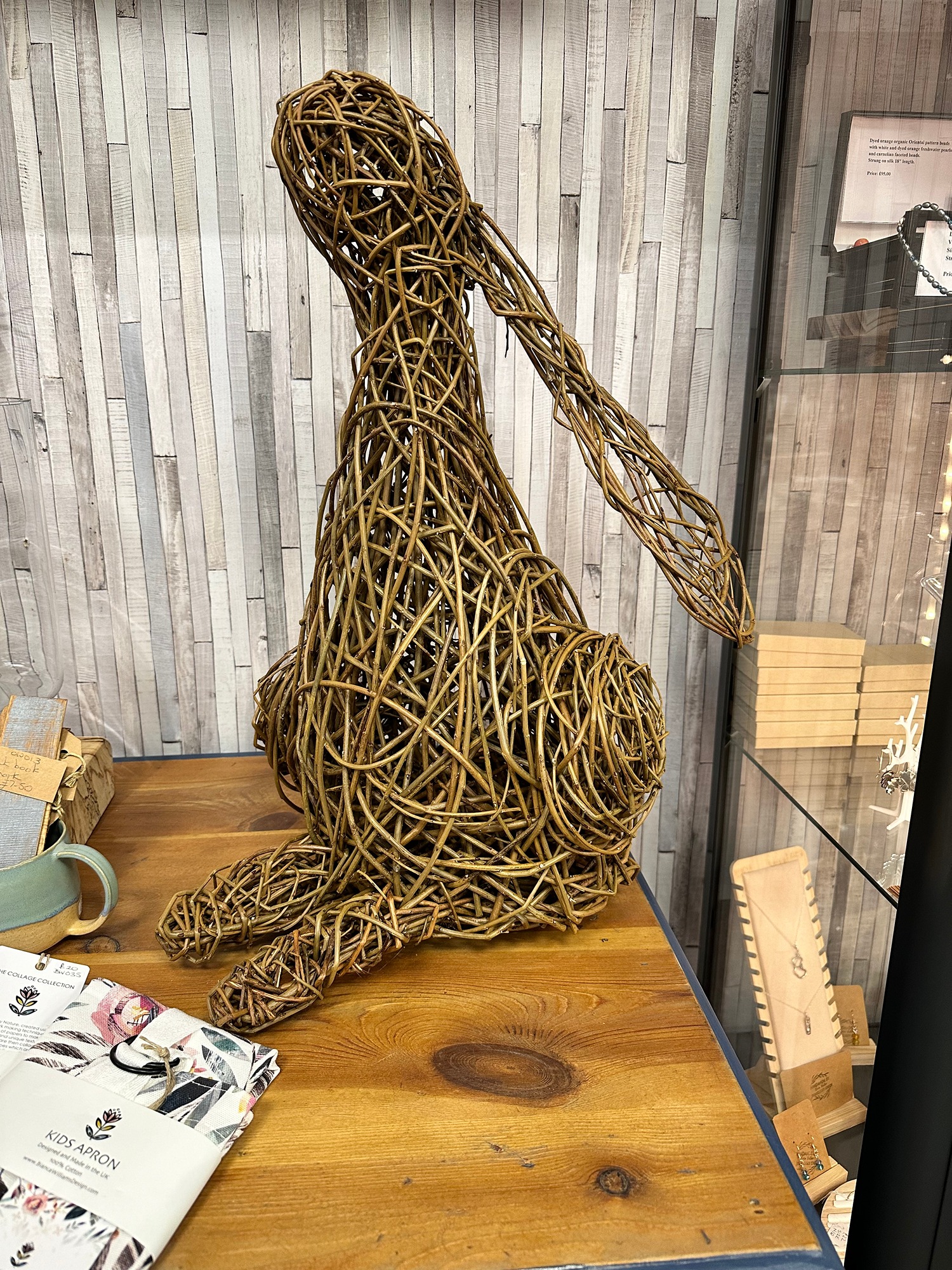 willow rabbit sculpture  sitting on path with grass behind