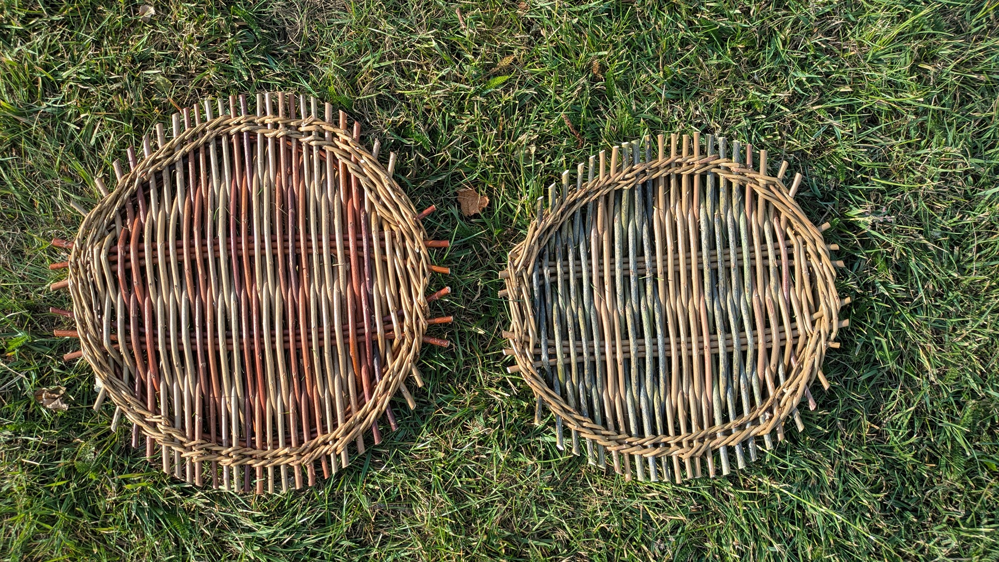 2 catalan platters on grass , one is a rusty red and light brown the other a bluish tone and light brown