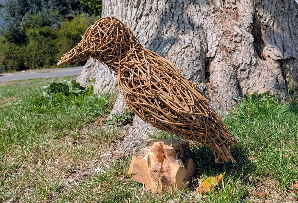 Willow Raven sculpture next to a treed
