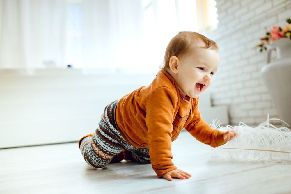 happy-child-orange-sweater-plays-with-feather-floor