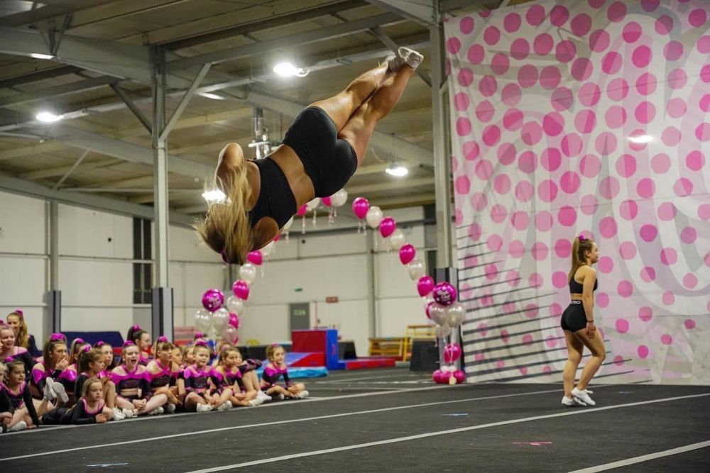 A girl  tumbling diagonally in the air in front of an audience.