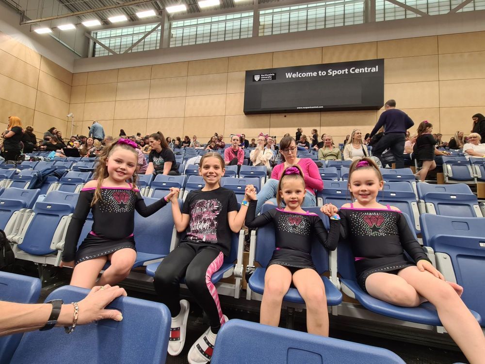 Four girls holding hands in audience seats.