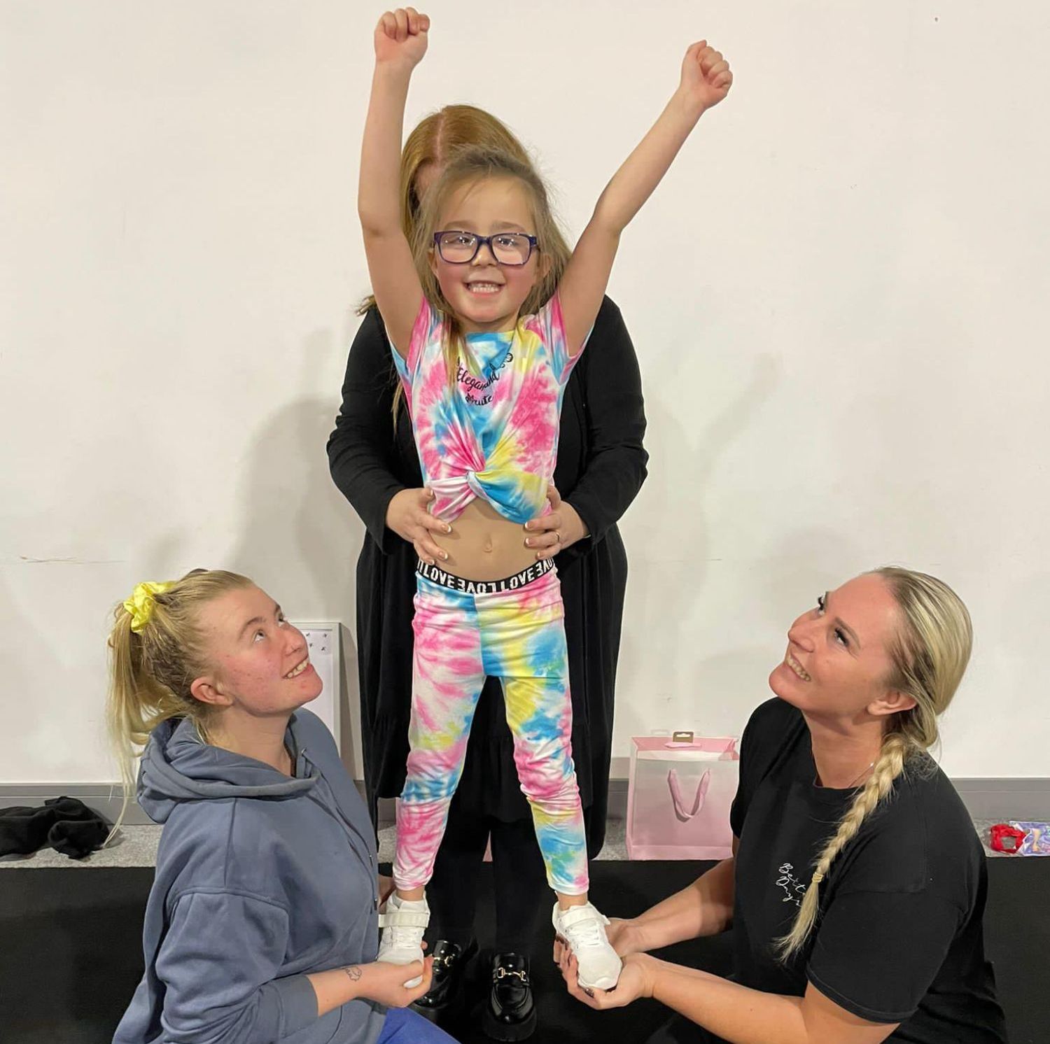 A girl being supported in a cheer position by  her family or carers