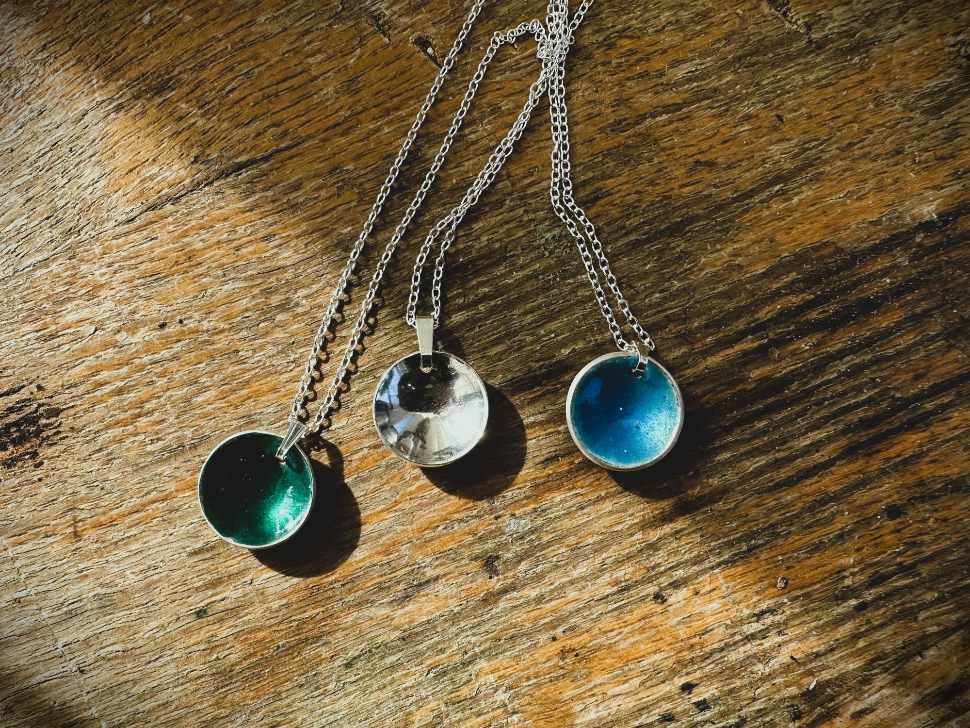 sterling silver domed pendants, two with transparent enamal and one naturally finished to a high polish