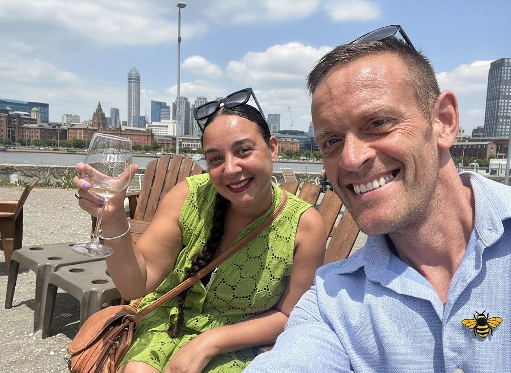 Davison & Brogan founders Chris and Rachel in Manchester; Chris wearing a Manchester Bee emblem, representing their journey from the UK to starting a gin brand in Frigiliana.