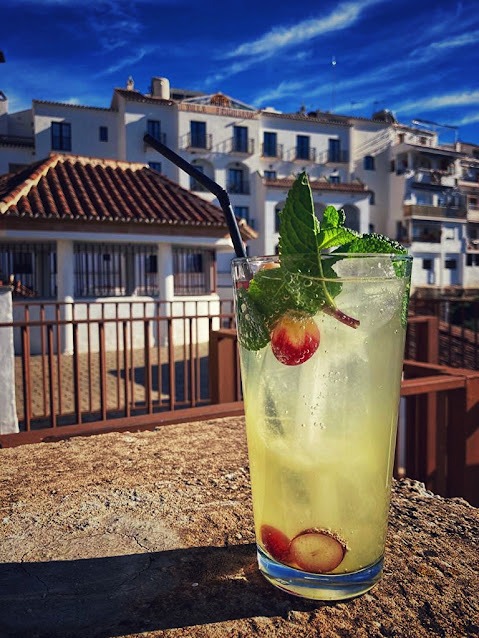 The Ginito cocktail made with Davison & Brogan Avocado Gin, fresh mint, and lime on a rustic wooden bar in Frigiliana.