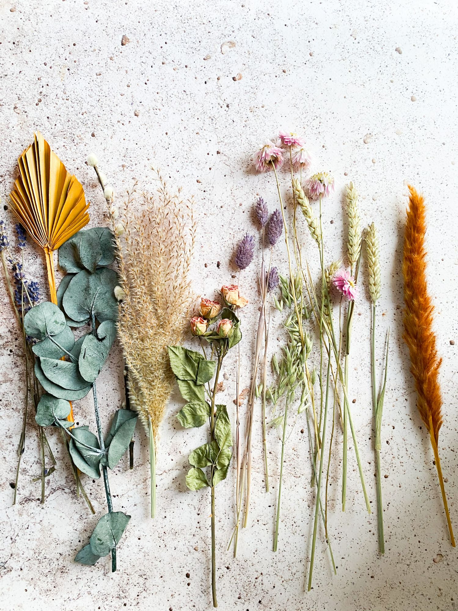 Dried spray roses, lavender, eucalyptus and grasses arranged on a table.