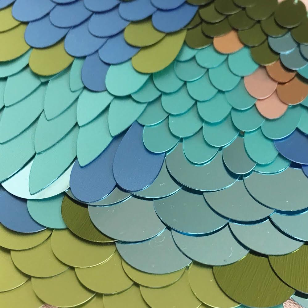 Recycled sequin embroidery design in blues and greens similar to a bird's wing