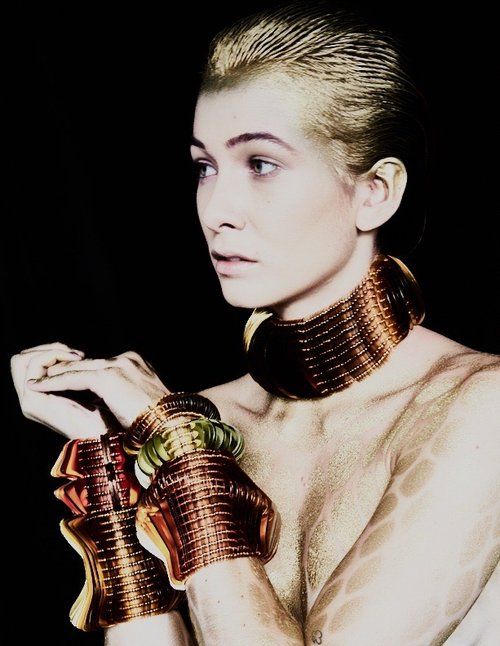 Model wearing large neck cuff and mulitple large wrist cuffs in bronze and gold