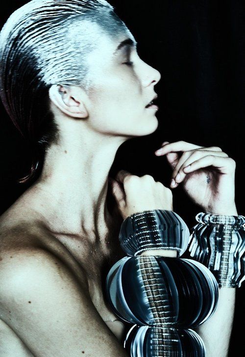 Model wearing mulitple large silver wrist cuffs made from layers of bespoke cut sequin film