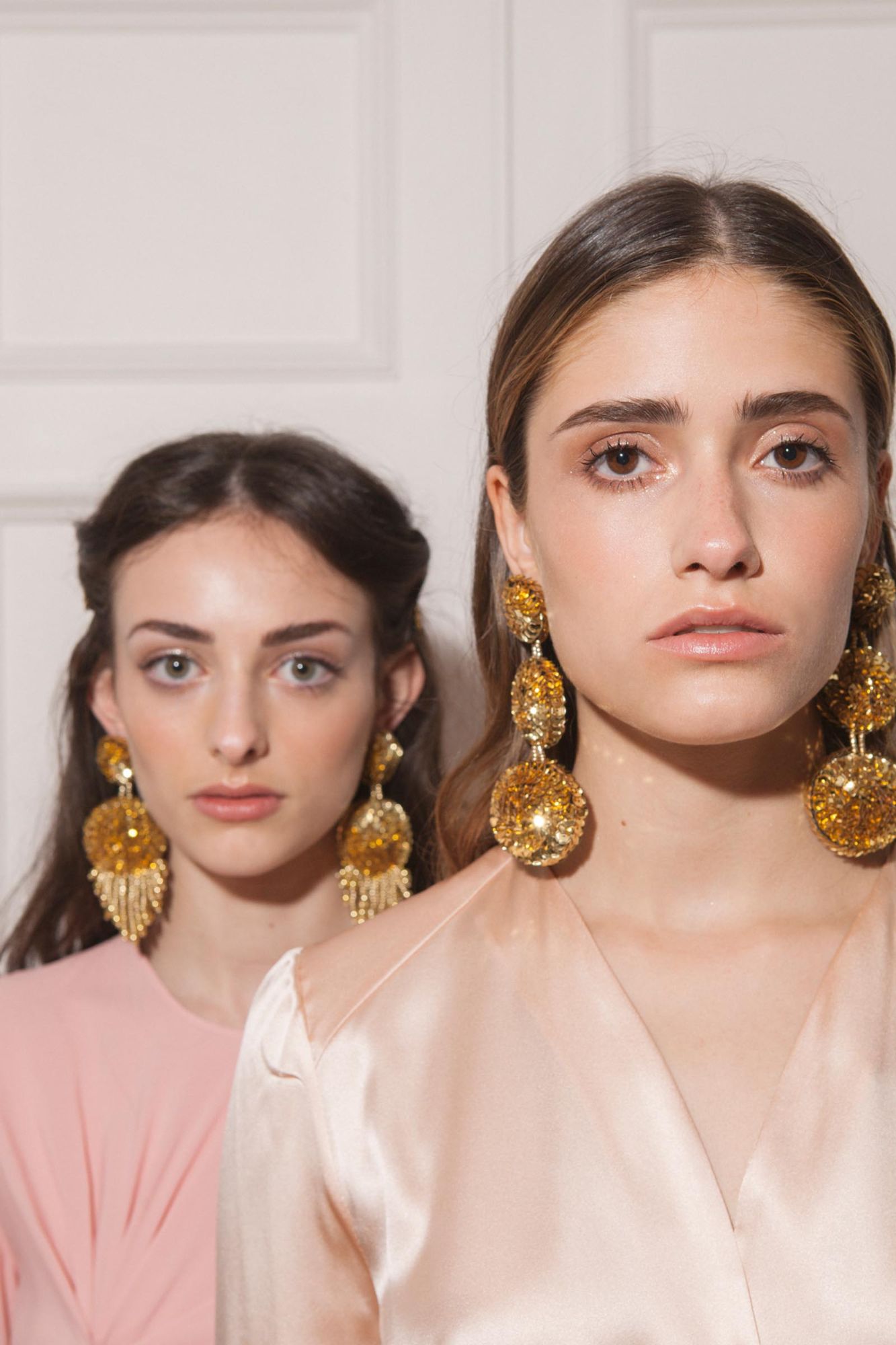 Two models wearing large gold sequin earrings