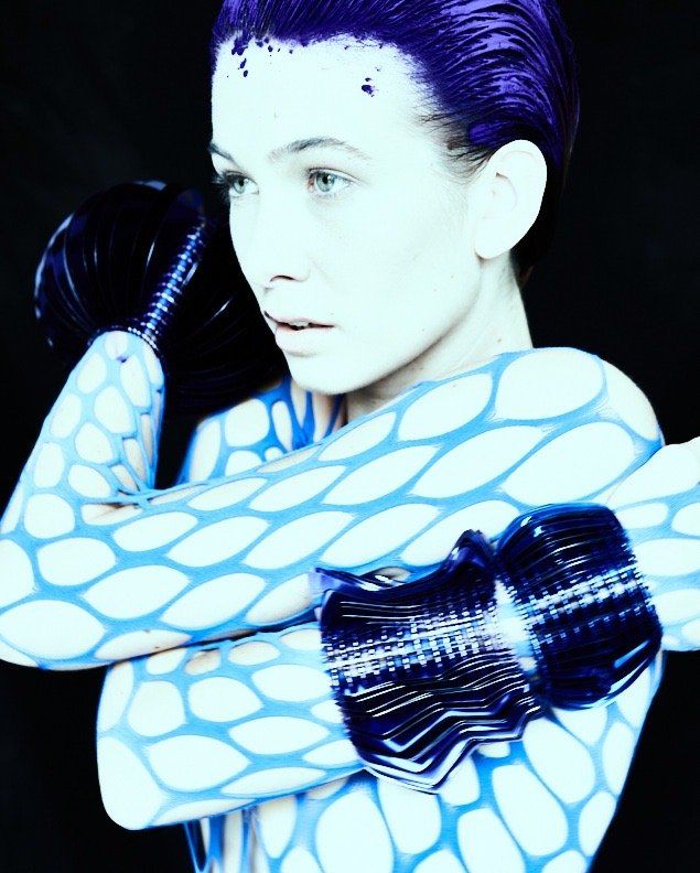 Model wearing mulitple large metallic blue wrist cuffs made from layers of bespoke cut sequin film