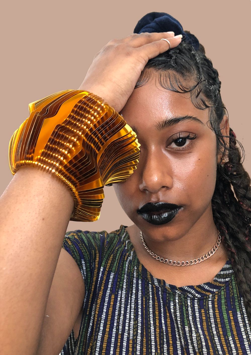 Model wearing a large gold wrist cuff made from layers of custom cut sequin film