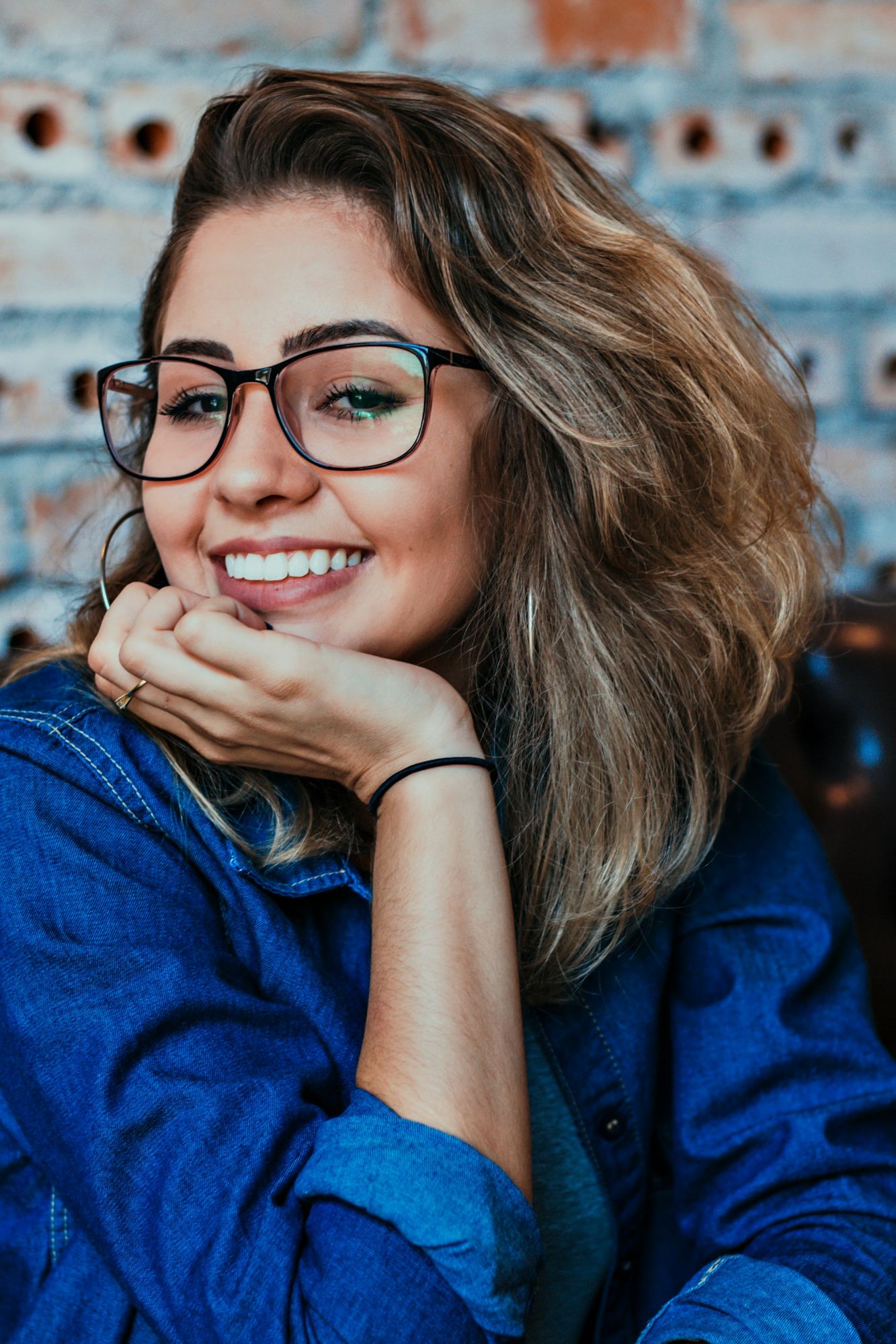 Brown-eyed woman with olive skin in glasses and blue denim shirt