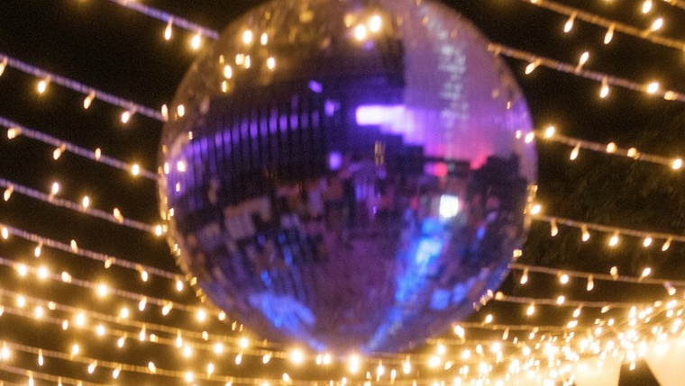 Disco glitter ball and party fairy lights strung across ceiling