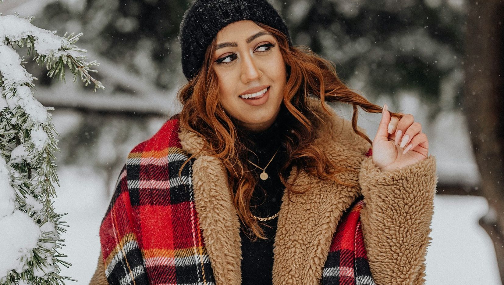 Woman in cosy teddy fleece jacket and tartan scarf in snowy winter scene