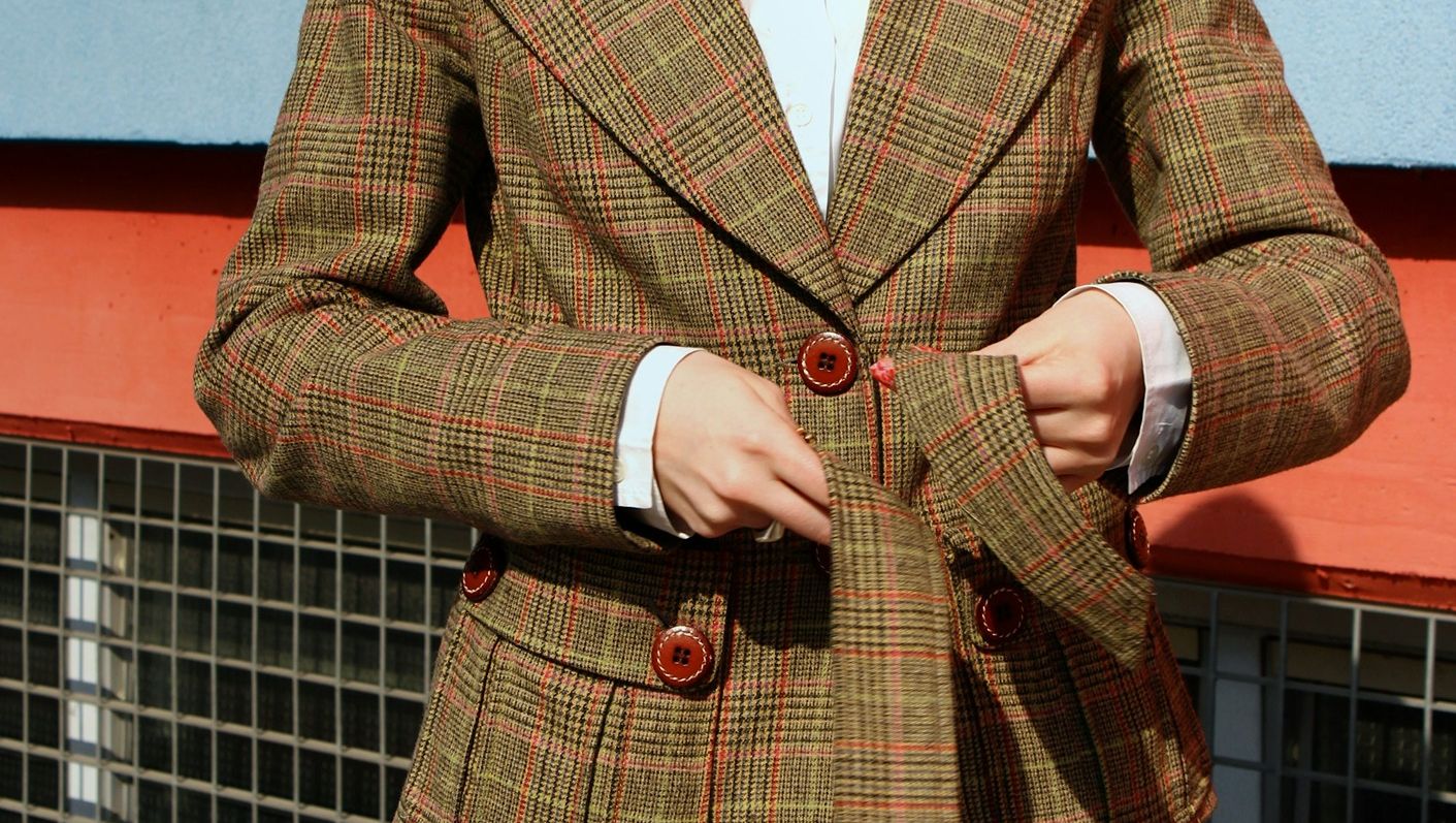 Woman in white shirt and tweed jacket tying belt