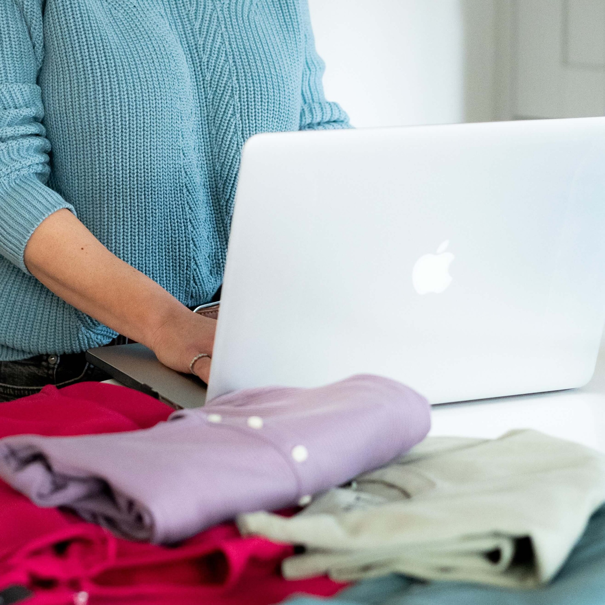 Personal colour analyst stylist wearing pink jumper selecting a beige jacket from a clothes rail