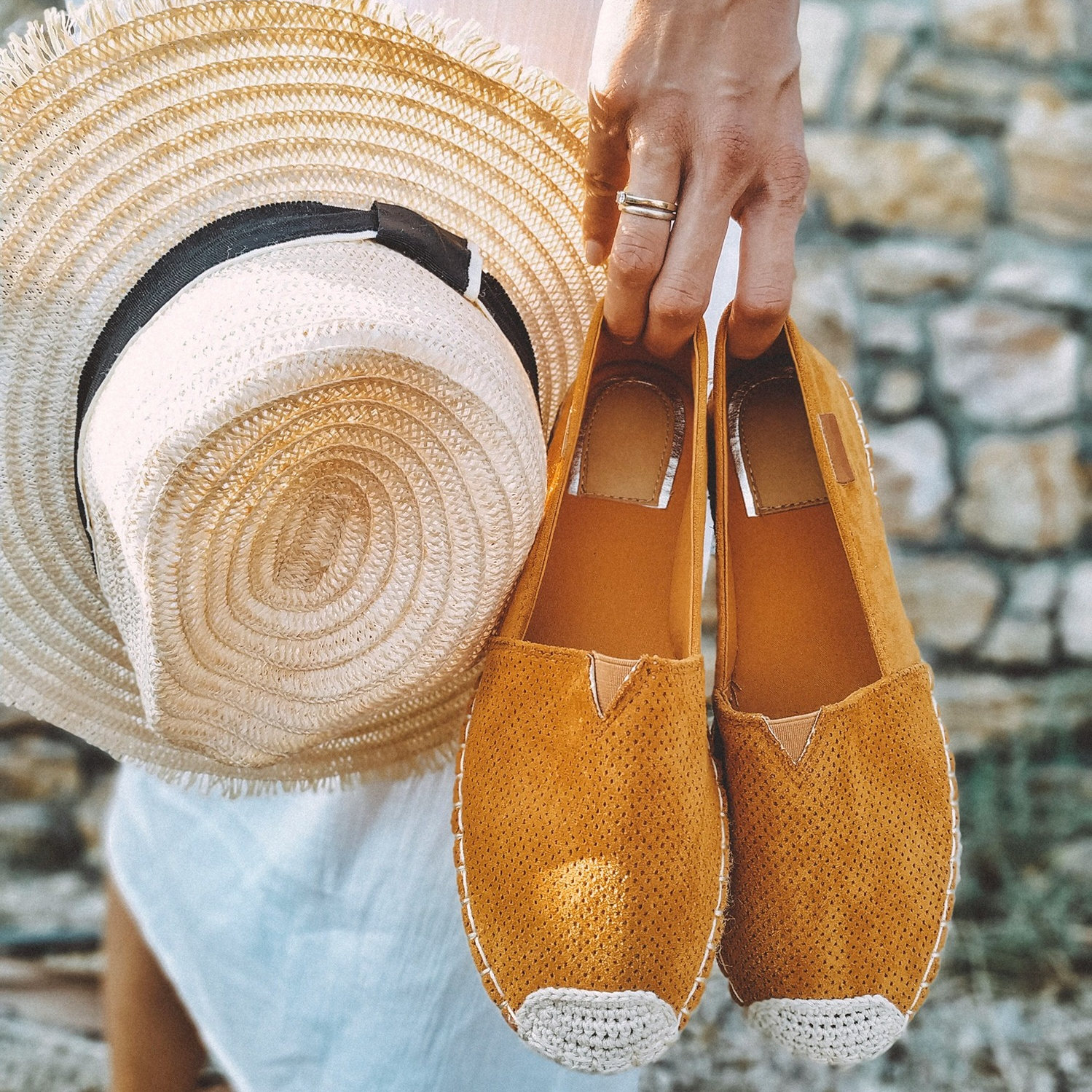 Close up of lady in white dress's tan espadrilles and straw hat