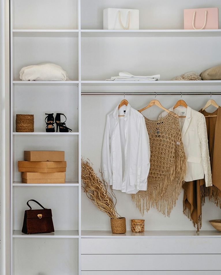 Woman with a curvy figure, light skin and blonde wavy hair, wearing a brown hat and floral co-ordinating top and bottoms in front of a bougainvillea plant