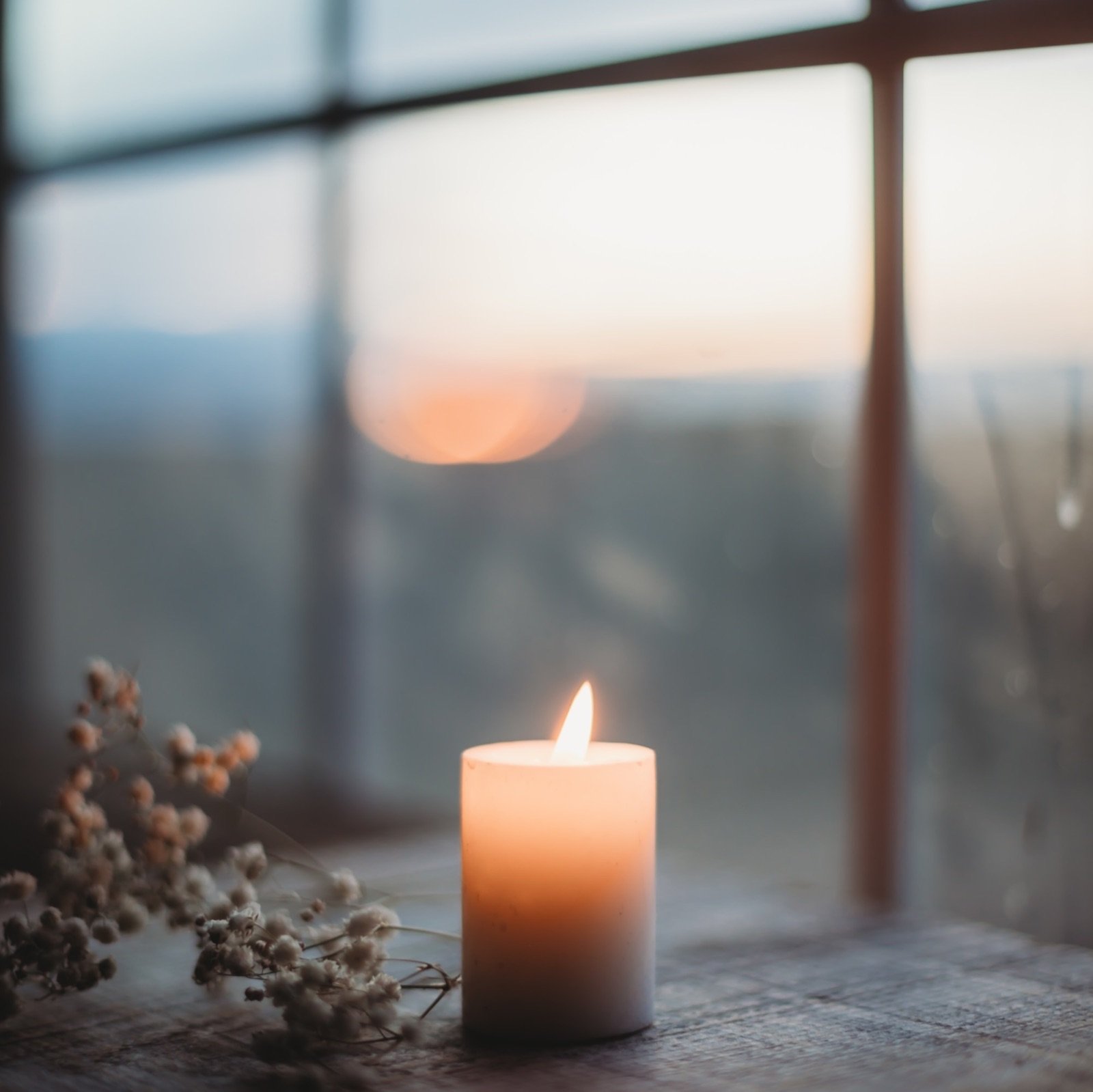 a-lit-candle-sitting-on-top-of-a-wooden-table-oDfeFV-Y2v0.jpg