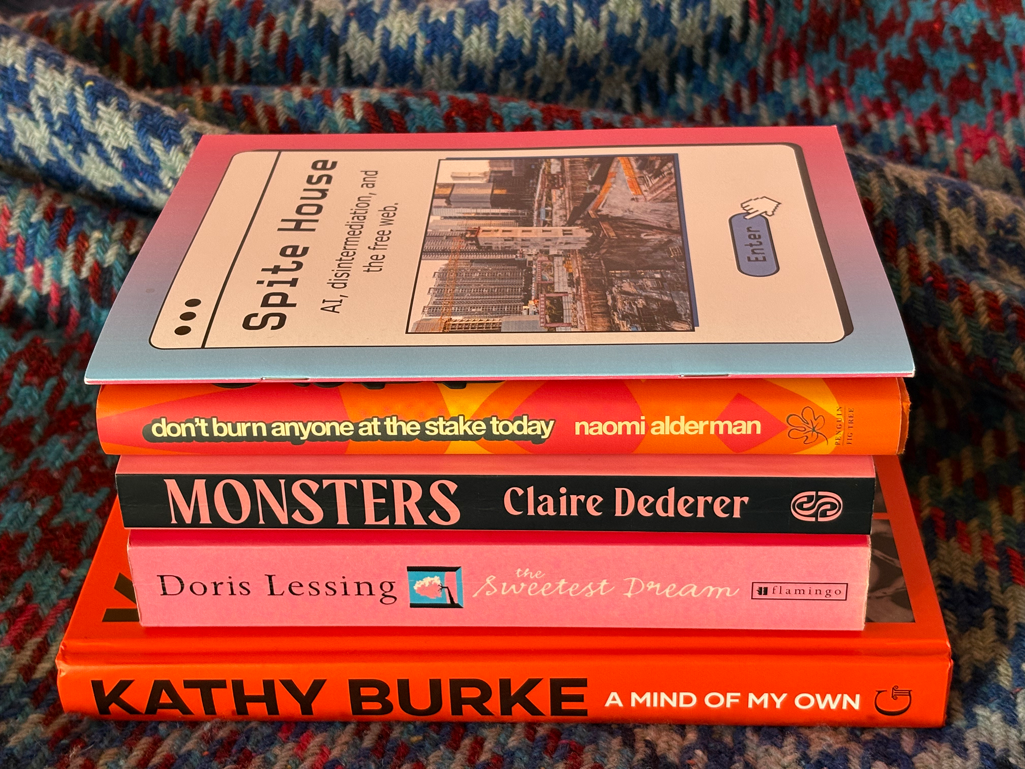 A stack of books on a blue and pink blanket. Kathy Burke A Mind of My Own, Dorris Lessing The Sweetest Thing, Monsters Claire Dederer, Naomi Alderman Don't Burn Anyone At The Stake Today, AI, disintermediation, and the free web.