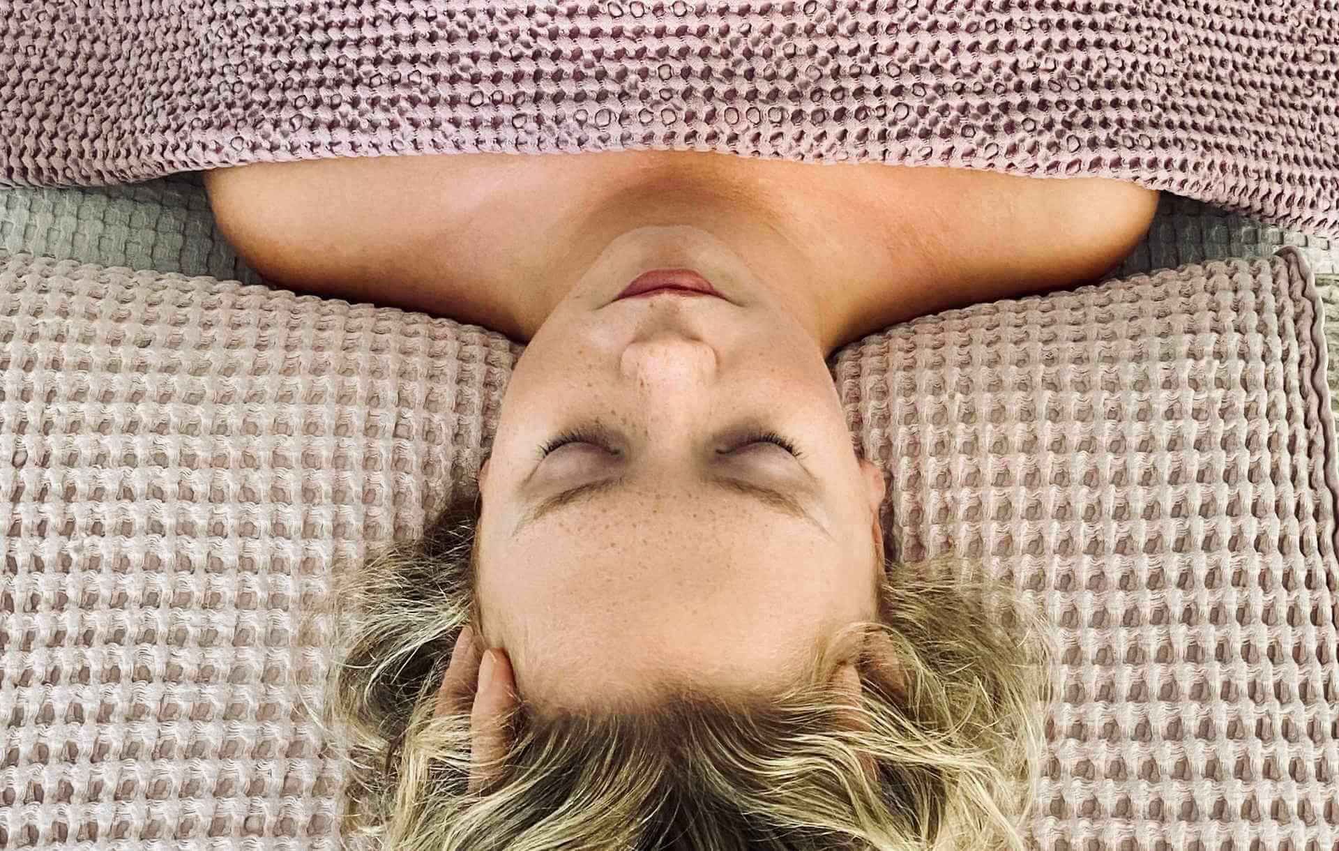 Client relaxing during a Lucyâs Facials treatment, wrapped in a soft blanket with eyes closed.